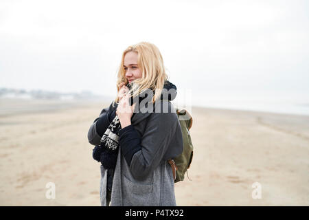 Ritratto di giovane donna bionda con zaino sulla spiaggia in inverno Foto Stock