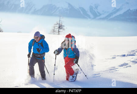 Austria, Tirolo, escursionisti con racchette da neve in esecuzione attraverso la neve Foto Stock