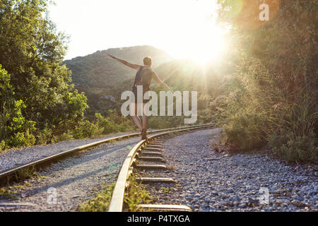 La Grecia, Pilion, Milies, vista posteriore del bilanciamento di donna lungo binari della ferrovia a scartamento ridotto al tramonto Foto Stock