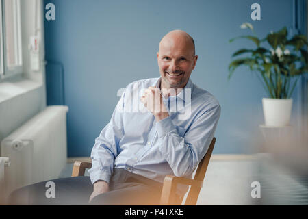 Ritratto di sorridente imprenditore maturo seduto in poltrona Foto Stock