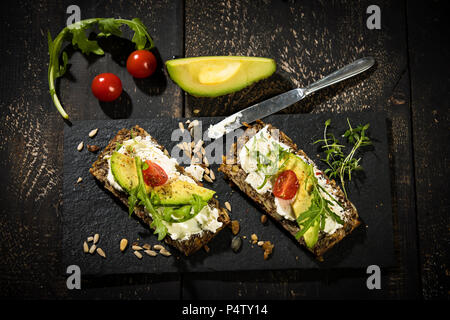 Onion il pane con la crema di formaggio, prosciutto di Parma, avocado, rucola, timo e pomodoro Foto Stock