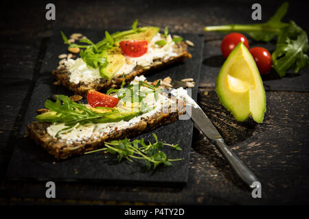 Onion il pane con la crema di formaggio, prosciutto di Parma, avocado, rucola, timo e pomodoro Foto Stock