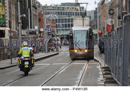 Garda su una motocicletta in prossimità di un treno Luas nel centro della città di Dublino, Irlanda Foto Stock
