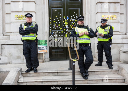 Londra, Regno Unito. 23 Giugno 2018.Anti-Brexit marzo e rally per un voto popolare nel centro di Londra. Poliziotti a guardia della porta anteriore del Cabinet Office dopo che era stata sfigurata con adesivi dai manifestanti. Foto Stock