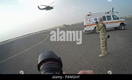 Sgt. Christopher Bigelow, un affari pubblici sottufficiale con la 316supporto comando (Expeditionary), 1 supporto comando (teatro), (destra), fotografie a UH-60 Blackhawk e MV-22 Osprey durante una comune formazione di salvataggio con Marines dal mezzo marino Tiltrotor squadrone - 364 (VMM-364), a Camp Arifjan, Kuwait, 8 maggio 2017. Foto Stock