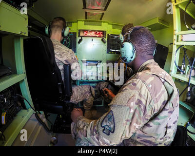 Sgt. La carità dal 3° Battaglione, 58o reggimento di aviazione siede nel retro osservando come due soldati del secondo battaglione Airfield Operations, 130Reggimento di aviazione (North Carolina National Guard), e l'ottantaduesima combattere la Brigata Aerea europee ad un aeromobile in arrivo durante un combinato combinati in un comune esercizio di preparazione a livello regionale Harnet Jetport, N.C., 10 maggio. Foto Stock