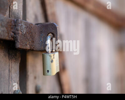 Close up di un lucchetto che fissano un arrugginito e stagionato porta in legno Foto Stock