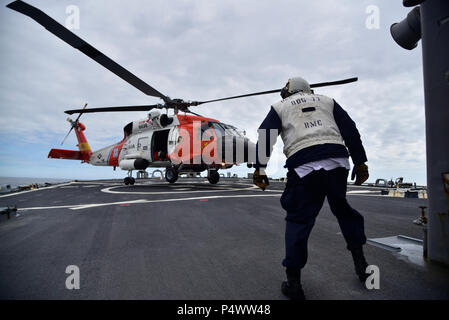 Golfo di Alaska - un capo di Boatswain Mate assegnato a Arleigh Burke-class missile destroyer USS O'Kane (DDG 77) osserva un U.S. Coast Guard MH-60T Jayhawk elicottero assegnato alla stazione di aria di Kodiak, Alaska, sbarco durante il ponte di volo operazioni nel Golfo di Alaska. Bordo settentrionale 2017 è l'Alaska's premiere joint-esercizio progettata per operazioni di pratica, le tecniche e le procedure nonché migliorare l'interoperabilità tra i servizi. Migliaia di partecipanti provenienti da tutti i servizi; marinai e soldati, aviatori, marine, e Guardia Costiera personale dal servizio attivo, Riserva e compit Foto Stock