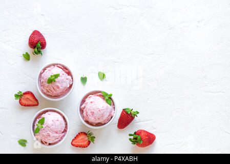 Gelato alla fragola e fragole fresche su sfondo bianco, vista dall'alto. Tre coppe di gelato alla fragola, sano dessert estivo. Foto Stock