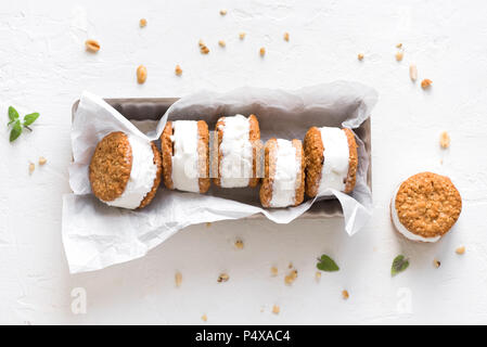 Panini di gelato con i dadi e i cookies integrali. Gelato di vaniglia fatto in casa panini su sfondo bianco. Foto Stock