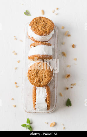Panini di gelato con i dadi e i cookies integrali. Gelato di vaniglia fatto in casa panini su sfondo bianco. Foto Stock