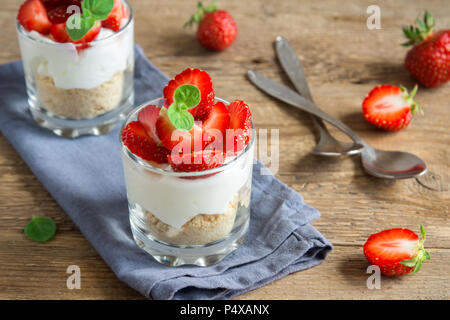 Zuppa di fragole mini dessert in bicchieri con fragole fresche e crema di formaggio su sfondo di legno. In casa sani potrion dessert. Foto Stock