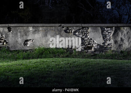 Il vecchio muro di pietra sbriciolamento di notte Foto Stock