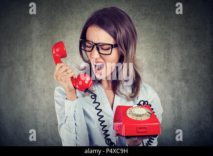 Ritratto di un giovane arrabbiato business donna urlare contro il telefono rosso Foto Stock