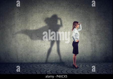 Vista laterale di una donna d'affari di immaginare di essere un super eroe cerca aspirava. Foto Stock