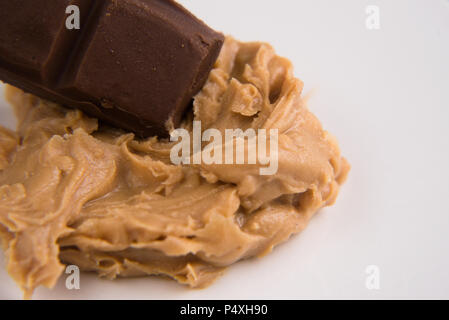 Primo piano di un burro di arachidi e barra di cioccolato su sfondo bianco Foto Stock