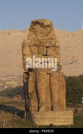 Colosso di Memnon. Statue in pietra raffigurante il faraone Amenhotep III (XIV secolo a.C.) in posizione seduta. Colosso orientale. Xviii dinastia. Nuovo Regno. Luxor. L'Egitto. Foto Stock