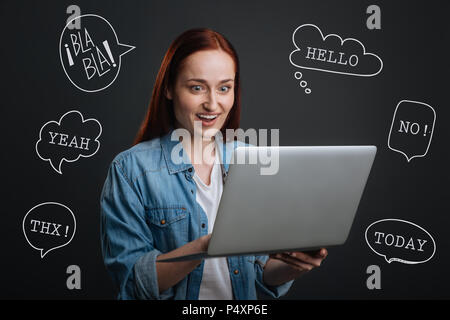 Famoso blogger in possesso di un computer portatile e la lettura dei commenti positivi Foto Stock