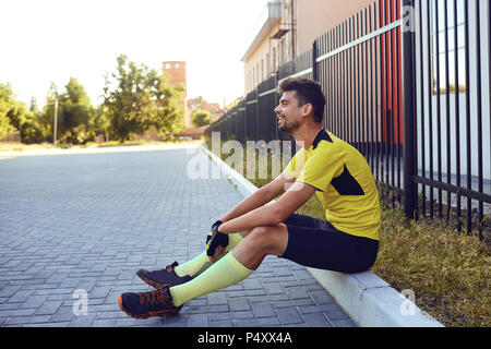 Un uomo in sportswear si siede sulla strada durante l. Foto Stock