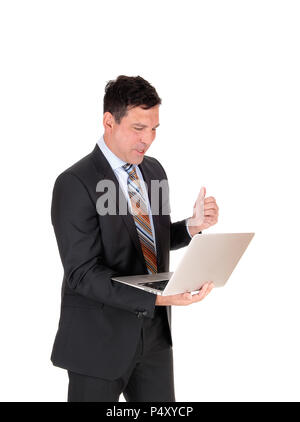 Un alto business man in piedi in un abito scuro e cravatta tenendo il suo laptop nella sua mano è felice che cosa il suo visto, isolato per sfondo bianco Foto Stock