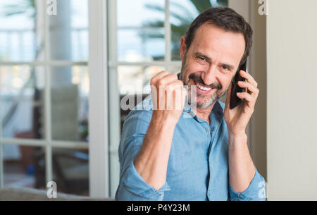 La mezza età uomo utilizza lo smartphone urlando orgoglioso e celebrando la vittoria e il successo molto eccitato, allietarla emozione Foto Stock