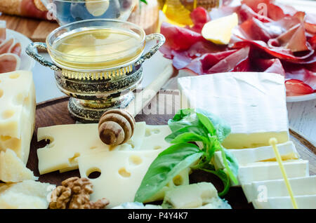 Vassoio di formaggi: Brie, Parmigiano, Cheddar, gouda, gorgonzola e altri con noci e miele sulla tavola di legno. Antipasti gustosi con diversi tipi di c Foto Stock