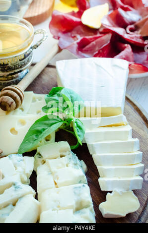 Vassoio di formaggi: Brie, Parmigiano, Cheddar, gouda, gorgonzola e altri con noci e miele sulla tavola di legno. Antipasti gustosi con diversi tipi di c Foto Stock