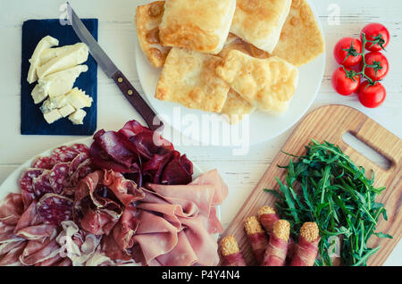 Italiano tradizionale di Emilia Romagna, Bologna regione antipasto crescentine fritte - impasto fritto, mangiare con gorgonzola e diversi tipi di carne e Foto Stock