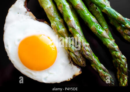 Uovo fritto e arrosto di asparagi freschi nella piastra nera. Pranzo sano concetto. Deliziosi e nutrienti mangiare. Vista dall'alto. Foto Stock