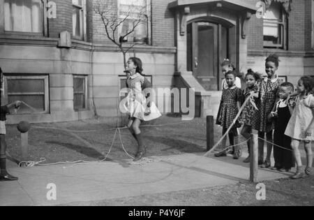 Un gruppo di ragazze Salto con la corda sul marciapiede, "Cintura nera' Quartiere, Chicago, Illinois, USA, Edwin Rosskam per ufficio di informazione di guerra, Aprile 1941 Foto Stock