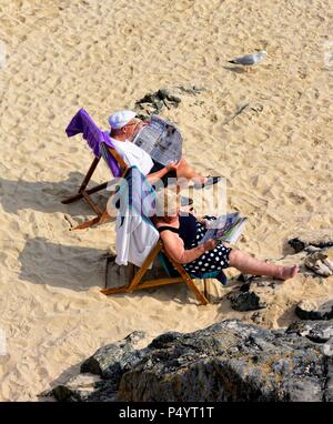 Coppia di anziani a prendere il sole sulla spiaggia di Porthgwidden St Ives Cornwall Inghilterra REGNO UNITO Foto Stock
