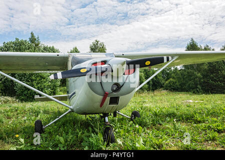 Un singolo motore aereo vicino - up è sull'erba verde del campo di aviazione di massa Foto Stock