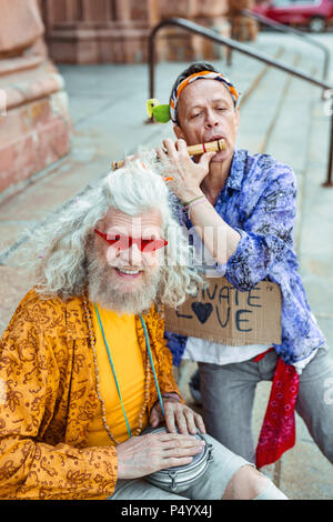 Sorridente hippy indossando giallo maglietta floreale unendo il suo amico Foto Stock