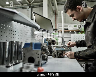 Lavoratore in fabbrica metallurgica misurando la testata con il calibro Foto Stock
