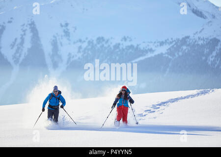 Austria, Tirolo, escursionisti con racchette da neve in esecuzione attraverso la neve Foto Stock