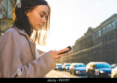 La Russia, San Pietroburgo, giovane donna utilizza lo smartphone nella città Foto Stock