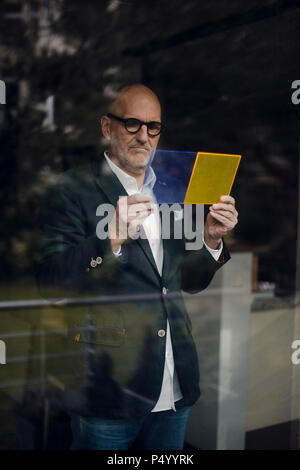 Senior Architect in piedi alla finestra, la scelta dei materiali Foto Stock