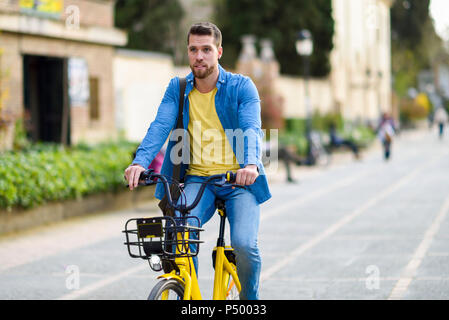 Giovane uomo equitazione noleggio bici in città Foto Stock