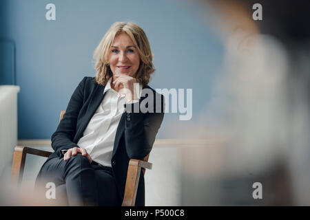 Ritratto di sorridere senior imprenditrice seduto in poltrona Foto Stock