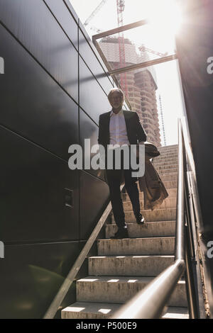 Imprenditore maturo camminando sulla scalinata della città Foto Stock