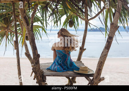 Giovane donna seduta sulla spiaggia, guardando il mare Foto Stock