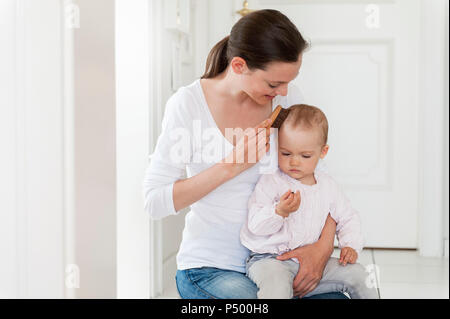La madre del bambino di spazzolatura dei capelli a casa Foto Stock