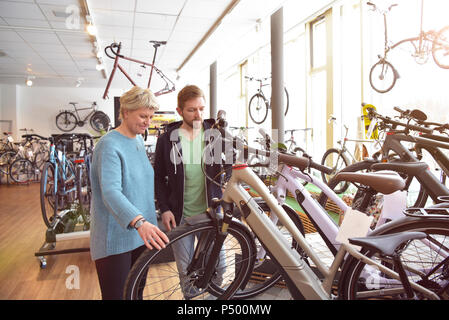 Venditore aiutare il cliente con e-bike Foto Stock