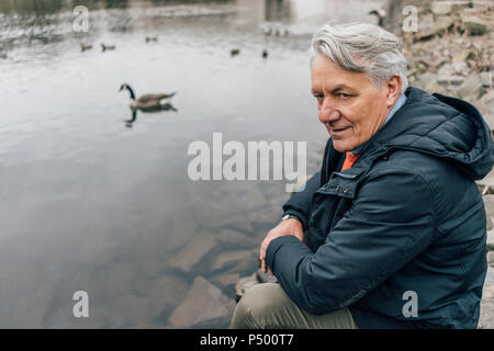 Uomo senior presso il riverside guardando lateralmente Foto Stock