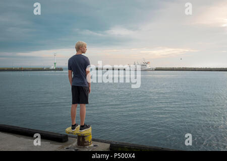 Polonia, Gdansk Bay, ragazzo adolescente permanente sulla banchina guardando a distanza Foto Stock