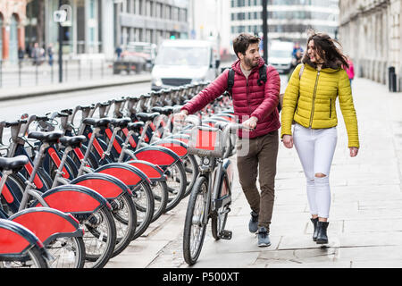 UK, Londra, giovane coppia con bicicletta bici da condividere stand passeggiate in città Foto Stock