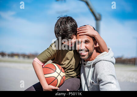 Ritratto di felice padre e figlio con basket all'aperto Foto Stock