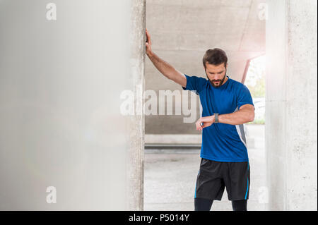 L'uomo avente una pausa dall'esecuzione controllando il tempo Foto Stock