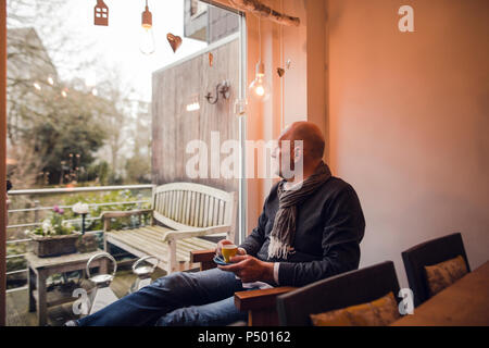 Senior uomo seduto a casa a bere caffè Foto Stock