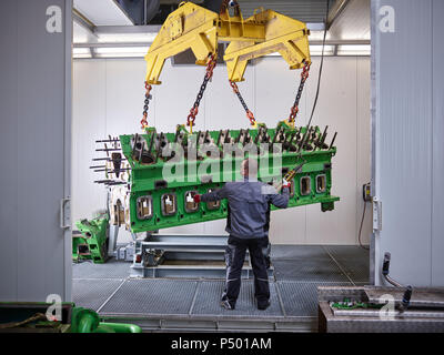 Lavoratore in fabbrica di sollevamento del blocco motore con la gru Foto Stock